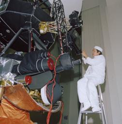 An engineer works on vibration acoustics and pyro shock testing for one of NASA's Voyager spacecraft on November 18, 1976. Several of the spacecraft's science instruments are visible at left.