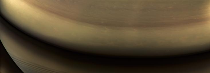This view of Saturn looks toward the planet's night side, lit in golden hues by sunlight reflected from the rings as seen by NASA's Cassini spacecraft.