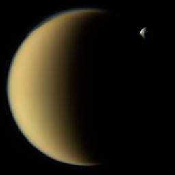 This image from NASA's Cassini spacecraft shows Saturn's moon Tethys disappearing behind Titan as observed by Cassini on Nov. 26, 2009. Tethys is about 660 miles (1,070 kilometers) across.