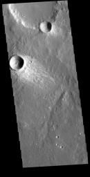 This image from NASA's Mars Odyssey shows a small region in Terra Sirenum. The bright material forming 'tails' behind the craters were created by surface winds funneled over and around the crater.