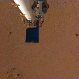 This image shows InSight's robotic arm, with its scoop and stowed grapple, poised above the Martian soil.