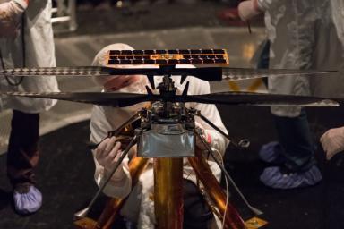 Members of the NASA Mars Helicopter team attach a thermal film to the exterior of the flight model of the Mars Helicopter. The image was taken on Feb. 1, 2019.
