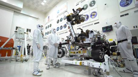 In the clean room of the Spacecraft Assembly Facility at JPL, the Mars 2020 rover's 7-foot-long (2.1-meter-long) arm maneuvers its 88-pound (40-kilogram) sensor-laden turret as it moves from a deployed to a stowed configuration.