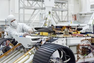 An engineer works on attaching NASA's Mars Helicopter to the belly of the Mars 2020 rover, which has been flipped over for that purpose, on Aug. 27, 2019, at the Jet Propulsion Laboratory in Pasadena, California.