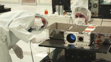 This image shows Electrical Test Engineer Esha Murty and Integration and Test Lead Cody Colley preparing the ASTERIA spacecraft for mass-properties measurements in April 2017.