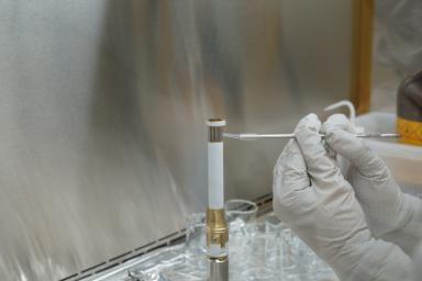 A technician working on the Mars 2020 mission takes a sample from the surface of sample tube 241, to test for contamination. The image was taken in a clean room facility at NASA's Jet Propulsion Laboratory, where the tubes were developed and assembled.