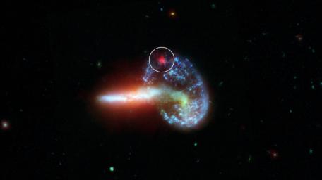 The image shows galaxy Arp 148, captured by NASA's Spitzer and Hubble telescopes. Specially processed Spitzer data is shown inside the white circle, revealing infrared light from a supernova hidden by dust.