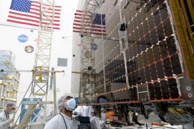 An engineer examines a panel on a stowed solar array on NASA's Psyche spacecraft prior to a deployment test in a clean at JPL. The panels are designed to work in low-light conditions, far from the Sun.