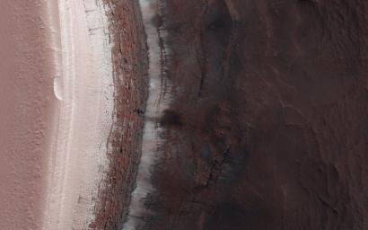 This image acquired on Febuary 15, 2023 by NASA's Mars Reconnaissance Orbiter shows a cliff face broken up into jagged blocks. Debris piles at the base of the cliff show where these blocks have fallen out.