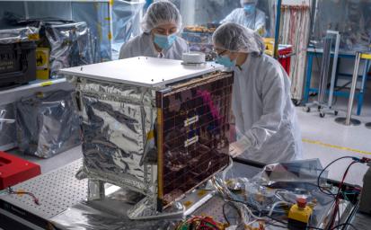 NASA's Farside Seismic Suite undergoes work in a JPL clean room in March, 2024. The instrument's two seismometers are packaged in a cube-within-a-cube structure. The shiny blanket is an outer insulating layer; the single solar panel provides power.