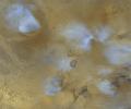 NASA's Mars Global Surveyor shows the volcanoes of the Tharsis region on Mars. The white or bluish-white features are clouds. Clouds are common over the larger Tharsis volcanoes in mid-afternoon.