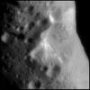 This image from NASA's NEAR Shoemaker shows an oblique view of Eros' large central crater. Brightness or albedo patterns on the walls of this crater are evident as are boulders inside this crater and the smaller nearby craters.