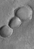 NASA's Mars Global Surveyor shows three aligned meteor impact craters on the floor of a much larger crater in the Noachis Terra region on Mars.