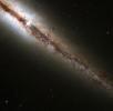 An amazing 'edge-on' view of a spiral galaxy 55 million light years from Earth has been captured by the Hubble Space Telescope. The image reveals in great detail huge clouds of dust and gas extending along and above the galaxy's main disk. 