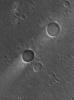 This image from NASA's Mars Global Surveyor spacecraft shows two impact craters of nearly equal size, plus their associated wind streaks. These occur in far eastern Chryse Planitia.
