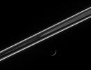 The dark side of the ringplane glows with scattered light, including the luminous F ring, which shines like a rope of brilliant neon. Below, Dione presents an exquisitely thin crescent in this image taken by NASA's Cassini spacecraft.