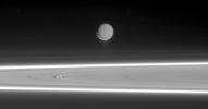 Lit by reflected light from Saturn, Enceladus appears to hover above the gleaming rings, its well-defined ice particle jets spraying a continuous hail of tiny ice grains as seen by NASA's Cassini spacecraft.
