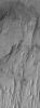NASA's Mars Global Surveyor shows erosional remnants of layered rock and large windblown ripples on the floor of a crater in the Tyrrhena Terra region of Mars. The layered rocks are most likely sedimentary.