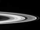 Saturn's sunlit rings gleam in the blackness as two icy moons cruise past in the foreground as seen by NASA's Cassini spacecraft.