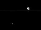 Two of Saturn's moons, Mimas and Rhea, regard each other across a vast distance in this view from NASA's Cassini spacecraft.