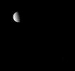 Two companion moons share the sky before NASA's Cassini spacecraft. Tethys is seen here with one of its two Trojan moons.