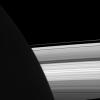 NASA's Cassini spacecraft looks past the night side of Saturn, dimly lit on the left of this image by ringshine, for a subtly distorted view of the planet's rings.