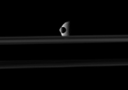 The small moon Mimas passes in front of the larger moon Rhea which is partly obscured by Saturn's rings in this image from NASA's Cassini spacecraft. Go to the Photojournal to view the animation.