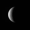 NASA's Cassini spacecraft pictures a crescent of Saturn's moon Rhea. Although craters dominate this particular view, the trailing hemisphere of Rhea also features wispy fractures.