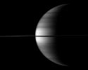 The highly reflective moon Enceladus appears as a bright dot beyond a crescent Saturn in this image from NASA's Cassini spacecraft. Enceladus is visible above the ringplane to the left of the center of the image.