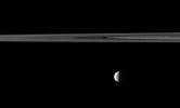 An illuminated quarter of the moon Tethys is imaged near a swath of Saturn's rings. Though the moon appears to be hanging directly below the rings, Tethys is actually farther from NASA's Cassini spacecraft, and the rings are in the foreground.