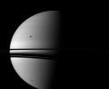Shadows adorn Saturn in this view from NASA's Cassini spacecraft, which also includes the moon Rhea, shown orbiting between the planet and the spacecraft and appears above the rings on the left of the image.