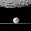 NASA's Cassini spacecraft looks past the cratered south polar area of Saturn's moon Rhea to spy the moon Dione and the planet's rings in the distance. Dione's 'wispy' terrain can be seen on the trailing hemisphere of that moon.