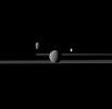 NASA's Cassini spacecraft observes three of Saturn's moons set against the darkened night side of the planet. Seen here are Rhea, closest to Cassini, Enceladus to right of Rhea, and Dione, left of Rhea.