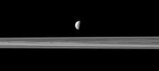 Saturn's fourth largest moon, Dione, appears like a solitary ornament suspended above the rings in view from NASA's Cassini spacecraft. The rings are closer to Cassini in this view, with Dione more distant.
