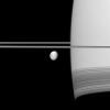 Saturn's moon Dione coasts along in its orbit appearing in front of its parent planet in this view from NASA's Cassini spacecraft. The wispy terrain on the trailing hemisphere of Dione can be seen on the left of the moon here.
