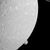 Saturn's moon Mimas peeps out from behind the larger moon Dione in this view from NASA's Cassini spacecraft.