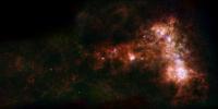 In combined data from ESA's Herschel and NASA's Spitzer telescopes, irregular distribution of dust in the Small Magellanic Cloud becomes clear. A stream of dust extends to left, known as the galaxy's 'wing,' and a bar of star formation appears to right.
