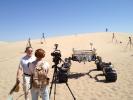 Michael Malin, left, principal investigator for three science cameras on NASA's Curiosity Mars rover, comments to a news reporter during tests with Curiosity's mobility-test stand-in, Scarecrow, on Dumont Dunes in California's Mojave Desert.