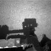 This is the first image taken by the Navigation cameras on NASA's Curiosity rover. It shows the shadow of the rover's now-upright mast in the center, and the arm's shadow at left. The arm itself can be seen in the foreground.