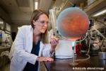 In this image, an artistic version of a hot Jupiter inspired by computer simulations has been inserted into a photo showing a Spitzer researcher, Heather Knutson, in a laboratory.