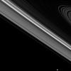 While the moon Epimetheus passes by, beyond the edge of Saturn's main rings, the tiny moon Daphnis carries on its orbit within the Keeler gap of the A ring in this image from NASA's Cassini spacecraft.