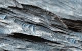 This basin in Ceti Mensa, as seen by NASA's Mars Reconnaissance Orbiter, exposes concentric rings in the sedimentary layers. Dark sand ripples and textures in the bedrock suggesting wind scouring are also apparent.