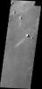 A long, narrow windstreak has formed in the lee of this hill in the Tartarus Montes. Several small dark craters also have windstreaks as shown by NASA's 2001 Mars Odyssey spacecraft.