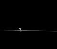 Dione appears cut in two by Saturn's razor-thin rings, seen nearly edge-on in a view from NASA's Cassini spacecraft.