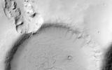 This image NASA's Mars Reconnaissance Orbiter shows an impact crater that was cut by lava in the Elysium Planitia region of Mars. It looks relatively flat, with a shallow floor, rough surface texture, and possible cooling cracks.