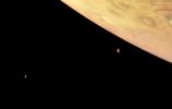This color-enhanced image of Jupiter and two of its largest moons, Io and Europa, was captured by NASA's Juno spacecraft as it performed its eighth flyby of the gas giant planet.