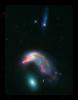This image of distant interacting galaxies, known collectively as Arp 142, bears an uncanny resemblance to a penguin guarding an egg. Data from NASA's Spitzer and Hubble space telescopes have been combined to show these dramatic galaxies.