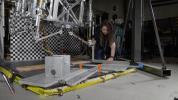 Morgan Montalvo, another JPL engineer, sets guardrails on the floor below the prototype in a test of a scenario where the lander would stub a toe against a rock while touching down on Mars.